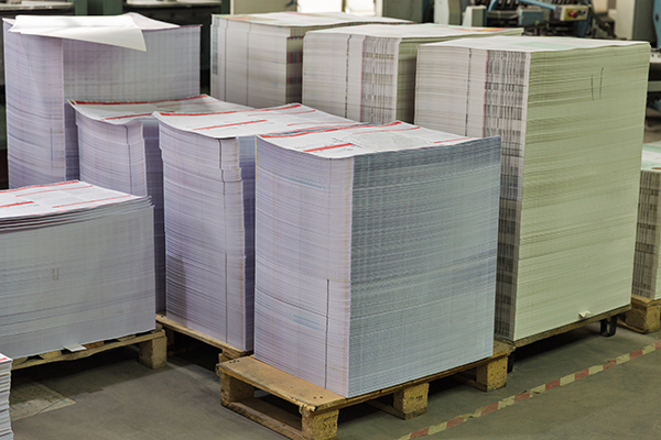 Stacks of printed sheets of cardboard on wooden pallets closeup.